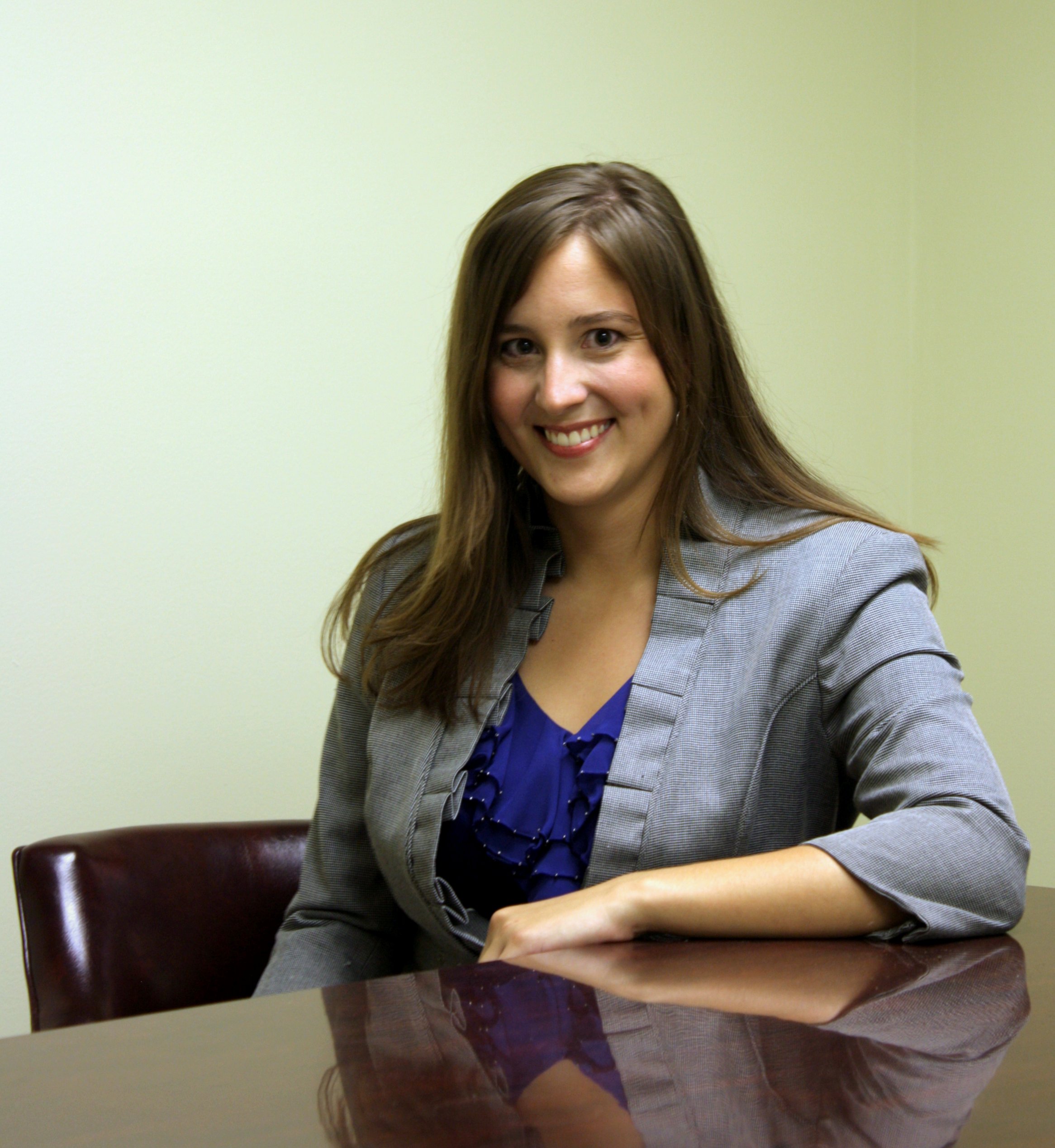 Alyssa Baxley, an attorney-at-law with Baxley Maniscalco, sits at a desk posing for a photo.