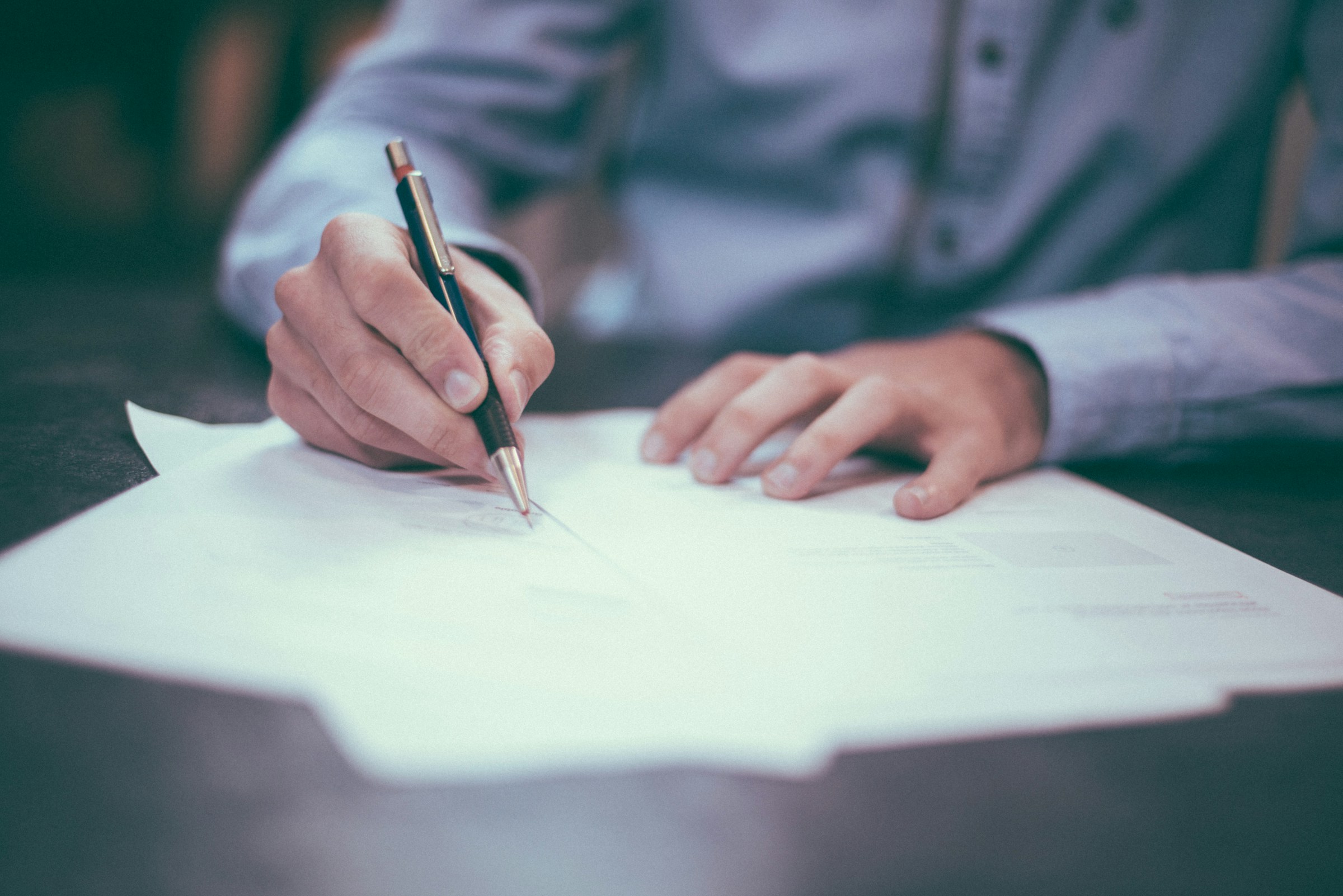 A man is seen filling out insurance forms on a desk.